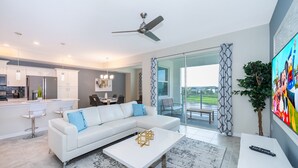 A modern living room with a white sofa, a coffee table, and a TV. - BE307  Storey Lake Condo 2 bed 2 bath  Free Waterpark (Kissimmee)