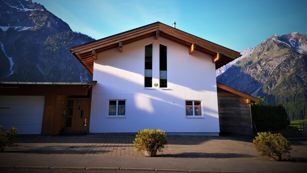 Une maison à deux étages avec un toit en pente, un garage et une allée.