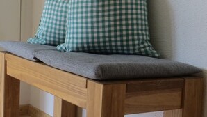 Un banc en bois avec un coussin gris et deux oreillers à carreaux verts et blancs.