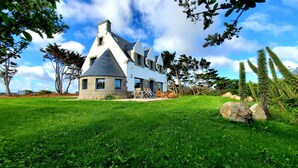 A house with a stone facade, multiple chimneys, and a grassy lawn.