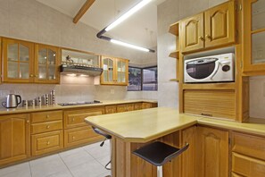 Uma cozinha com armários de madeira, micro-ondas e fogão a gás.