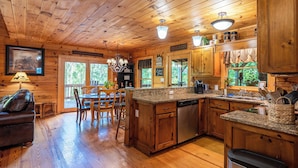 Interior de una cabaña de madera con cocina, comedor y sala de estar.