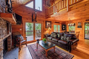 Un intérieur de chalet chaleureux avec une cheminée en pierre, un canapé en cuir et un plancher en bois.