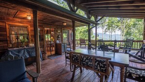 Una cabaña de madera con un porche cubierto, comedor y vistas al bosque circundante.