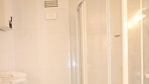 A bathroom with a toilet, a sink, a shower enclosure, and a toilet paper holder.
