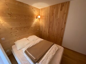 A small, cozy room with wooden walls and a single bed.