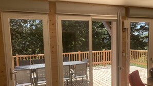 A wooden deck with outdoor furniture, including a table and chairs, and a sliding glass door leading to the deck. - Appartement Rocher du Cerf T5 (Le Lioran)