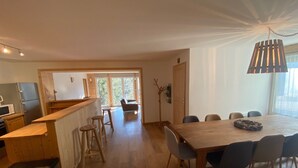 A spacious kitchen with wooden countertops, a dining area with a large table and chairs, and a view through a glass door to an outdoor area. - Appartement Rocher du Cerf T5 (Le Lioran)