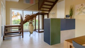 A spacious room with a wooden staircase, a large window, and a potted plant.