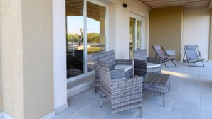 A covered patio with wicker furniture and a glass door leading to an outdoor area.