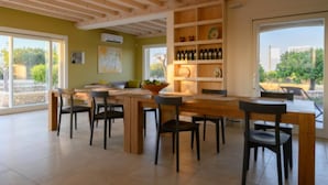 A spacious dining area with a wooden table and chairs, a built-in wine rack, and large windows offering a view of the outdoors.