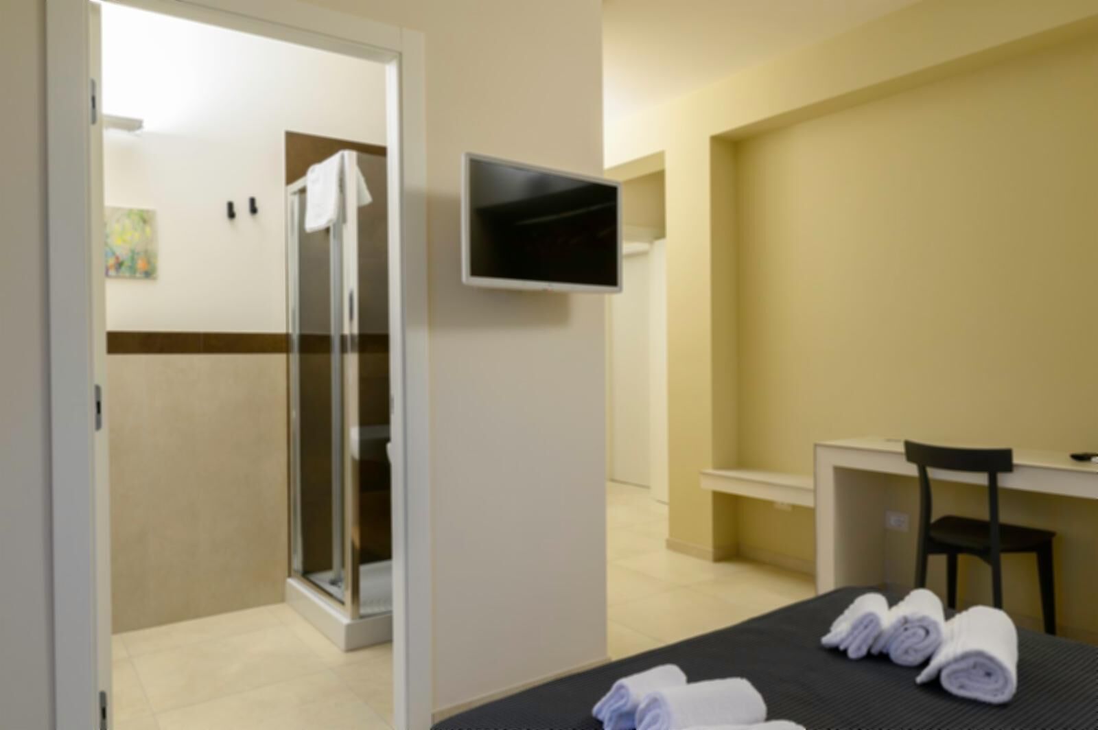 Een hotelkamer met een bed, bureau, stoel, televisie en douche.