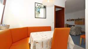 A dining area with orange furniture, a table with a white tablecloth, and a hanging light fixture. - App. Arius 10 on the beach (Westerland)