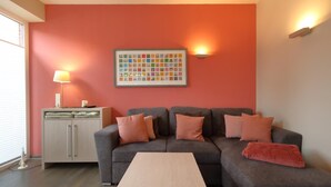 Una sala de estar con un sofá gris, una mesa de centro de madera y un mueble con una lámpara.