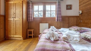 Une pièce en bois avec un lit, une armoire, un radiateur et une fenêtre avec des rideaux.