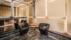 Een modern interieur met een marmeren vloer, zwarte stoelen, een kleine ronde tafel en een groot raam met uitzicht op het interieur.