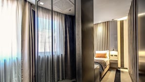 Een moderne hotelkamer met een bed, nachtkastje en gordijnen.