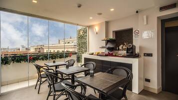 A modern dining area with a view of the city, featuring a bar, seating, and a large window.