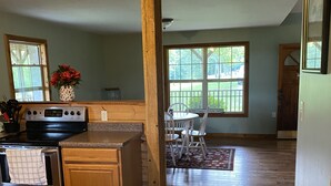 A kitchen with wooden cabinets, a stove, and a dining area with a table and chairs.