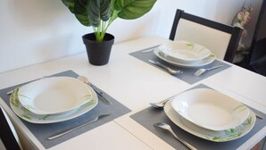 Uma mesa de jantar com quatro pratos, duas garfos, duas facas e um vaso de planta.