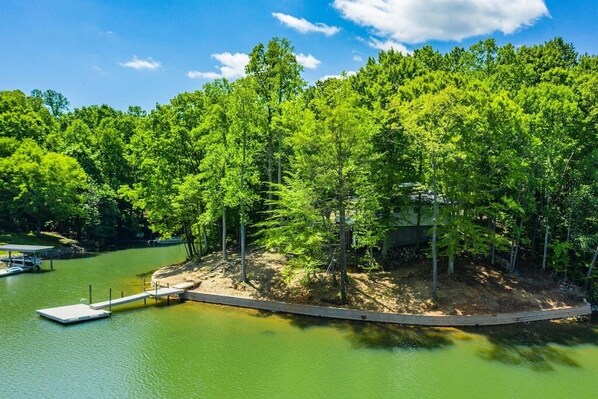 A lakeside cabin surrounded by dense forest, with a dock extending into the water. - PRIVATE PENINSULA on LAKE NORMAN Pet Friendly! (Denver)