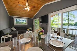 A dining area with a table set for four, a sofa, and a TV mounted on the wall. - PRIVATE PENINSULA on LAKE NORMAN Pet Friendly! (Denver)