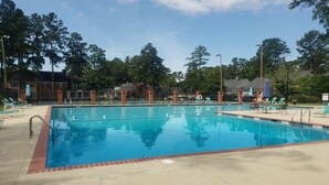 Ein rechteckiger Swimmingpool mit einer gefliesten Kante, umgeben von Liegestühlen und Sonnenschirmen.