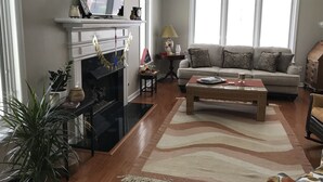 Ein Wohnzimmer mit Kamin, Fernseher, Sofa und Couchtisch.
