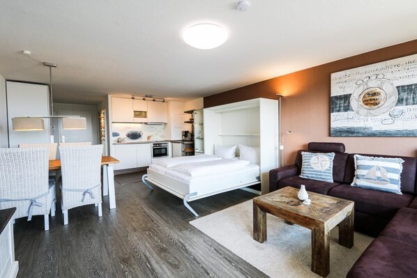 A modern, compact living space with a kitchenette, a dining area, and a seating area with a couch and coffee table.