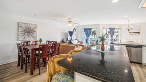 Een moderne keuken met een centraal eiland, een eetgedeelte met houten stoelen en een zithoek met een bank en salontafel.