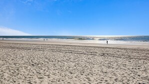 Een strand met een uitgestrekt zandgebied en een helderblauwe lucht.