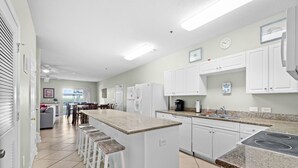 Una cocina moderna con armarios blancos, encimera de granito y una isla central con taburetes.