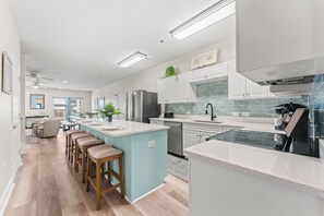 Una cocina moderna con una isla central, electrodomésticos de acero inoxidable y un comedor con taburetes de bar.