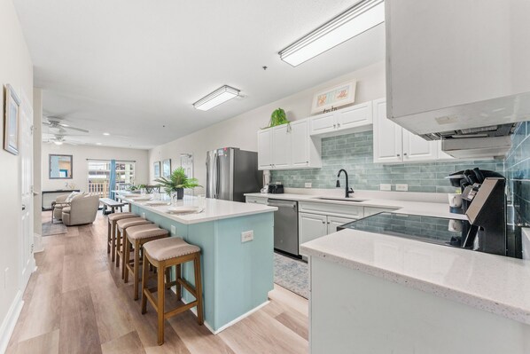 A modern kitchen with a central island, stainless steel appliances, and a dining area with bar stools.