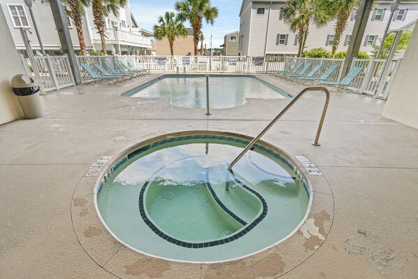 A swimming pool with a 3 ft depth marker, surrounded by lounge chairs and a white fence.
