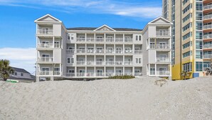 A multi-story hotel with balconies and a beach view.