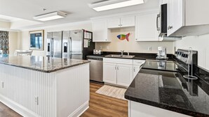 A modern kitchen with white cabinetry, stainless steel appliances, a granite countertop, and a backsplash.