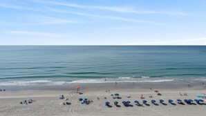 A beach with rows of umbrellas and people relaxing.