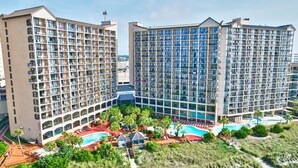 A hotel with multiple floors, a swimming pool, and outdoor seating areas.