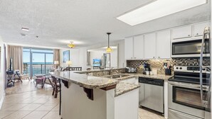 A modern kitchen with a central island, stainless steel appliances, and a view to the living area.
