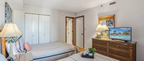 A hotel room with two beds, a television, a dresser, and a painting on the wall.