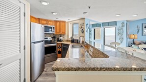 A modern kitchen with granite countertops, stainless steel appliances, wooden cabinets, and a large island.