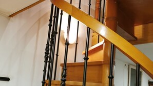 Una scala in legno con balaustre nere e una parete bianca sullo sfondo.