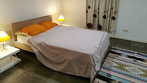 Una camera da letto con un letto, due abat-jour, un tappeto a motivi decorativi e una tenda con un disegno floreale.