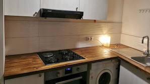 Una cucina funzionale con piano cottura a gas, forno integrato, lavatrice e lavello.