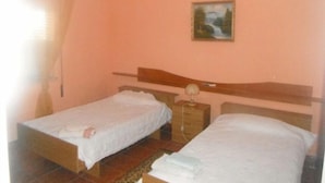 A bedroom with two single beds, a nightstand with a lamp, and a painting on the wall.