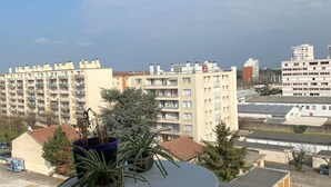 Un balcón con una mesa y plantas en macetas, con vistas a una zona residencial con edificios de varios pisos.