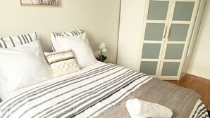 Una cama bien hecha con ropa de cama a rayas, una almohada blanca y una toalla doblada sobre la cama.