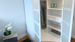 Una habitación con un armario blanco, una mesita de noche con una planta y una alfombra negra.