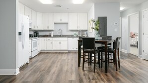 A modern kitchen with white cabinets, a dining table with chairs, and a wooden floor. - Nature Lodge - Dreamer - with Hiwassee River Access (Calhoun)
